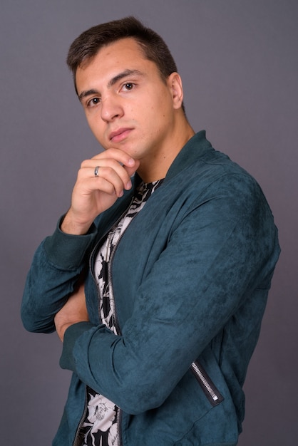 Profile view of young handsome man against gray background