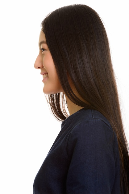 Profile view of young happy Asian teenage girl smiling