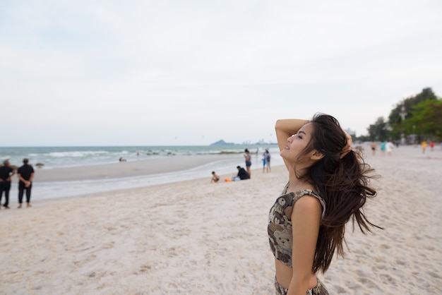 Profile view of young happy beautiful Asian woman smiling