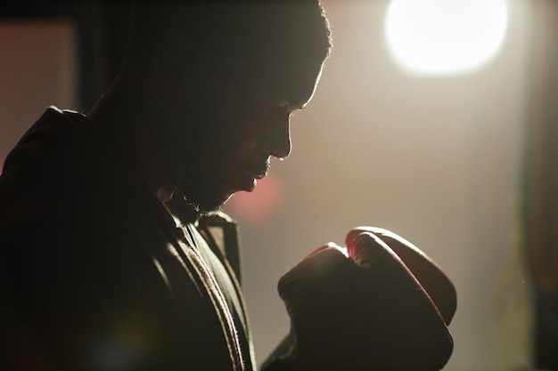 Profile view of young strong african american man in boxing gloves