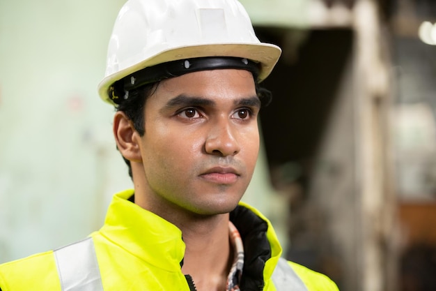 Profile view of young technician in checked shirt inspecting industrial machine