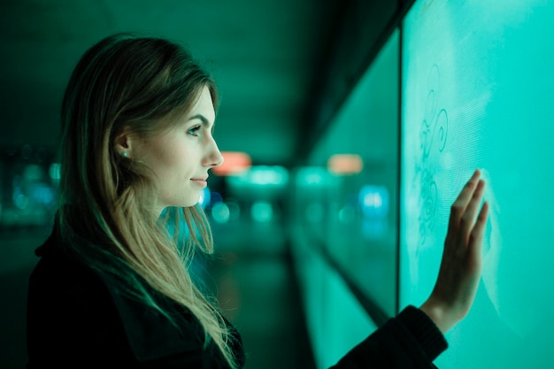 Photo profile view of young woman touching green computer monitor