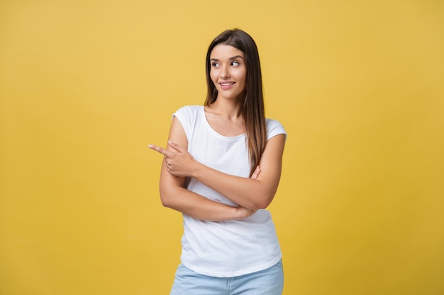 Profile of a woman pointing on copy space for an advertisement isolated on a yellow background