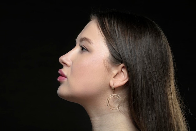 Profile of a young female model with perfect sensual lips and closed eyes on a black background