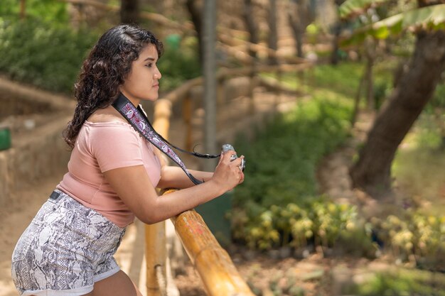 Profile of a young woman with a camera in a park