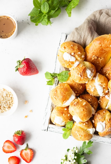 Profiteroles (choux à la crème) - French choux pastry balls with cottage cheese and cream with strawberry, mint and cup of coffee.