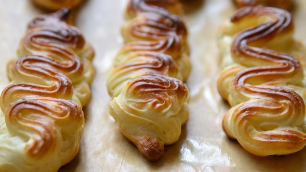 베이킹 팬에 크림이 없는 Profiteroles 또는 eclairs는 검은색 배경을 닫습니다.xAxA