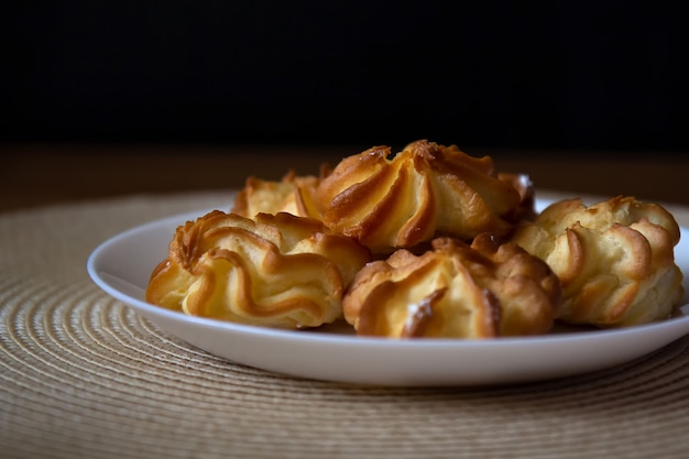 Profiteroles met room in een bord staan op een rieten servet