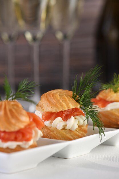 Profiteroles stuffed with cream cheese and salmon, decorated with a sprig of dill. Close-up