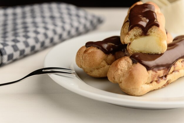 Profiteroles with butter cream and chocolate topping on the plate