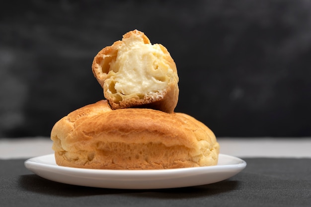 Profiteroles with curd filling. Homemade baking. Dessert eclairs on black background. Close up