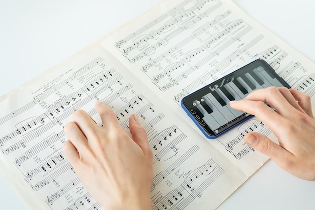 ピアノ ピアノ スコアを演奏する電話のプログラム 紙の上の音符 スマートフォンの練習用プログラム