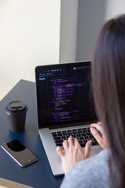 A programmer coding on a laptop in the workplace