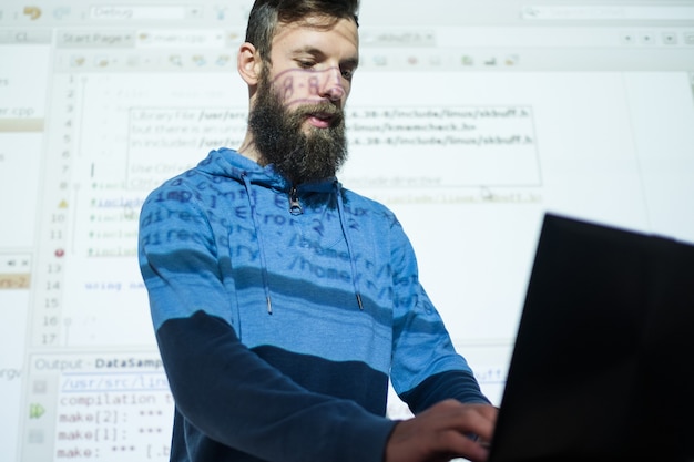 Foto corsi per programmatori presso il centro educativo uomo che guarda nel laptop la sua presentazione in sottofondo