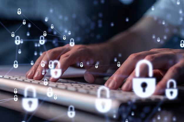 A programmer is typing a code on a keyboard to protect a cyber security from hacker attacks and save clients confidential data Padlock Hologram icons over the typing hands
