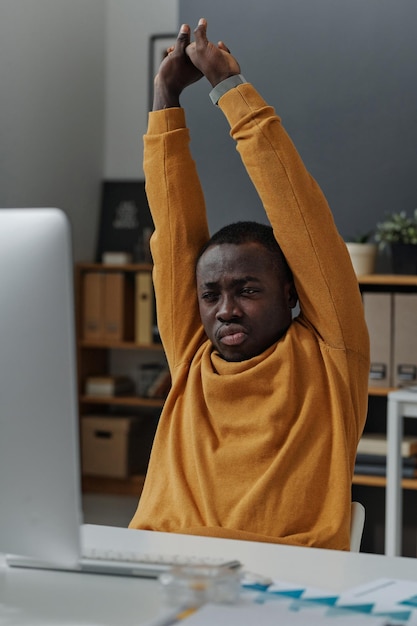 Programmer stretching at his workplace at office