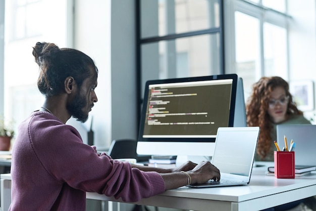 Programmer typing on laptop in IT office