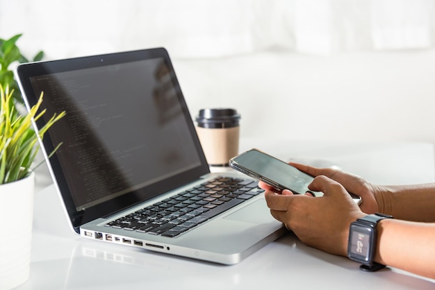 Programmer woman looking mobile phone program code at workplace