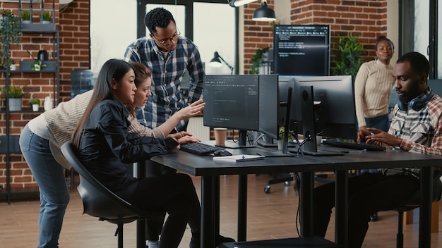 Programmeurs die samenwerken aan een algoritme voor het samenstellen van groepsprojecten voor een nieuwe gebruikersinterface voor cloud computing op computerschermen. Gemengd team van software-ingenieurs brainstormen ideeën kijken naar lopende code.