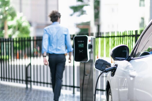 Progressief concept van focus EV auto bij laadstation met onscherpte man achtergrond