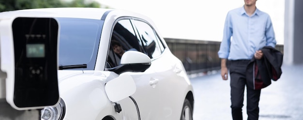 Progressief concept van focus EV auto bij laadstation met onscherpte man achtergrond