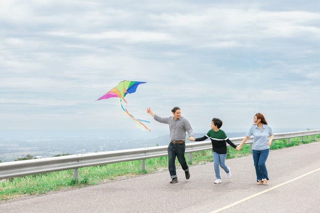 Progressief gelukkig familievakantieconcept met buiten vliegende vlieger op de weg