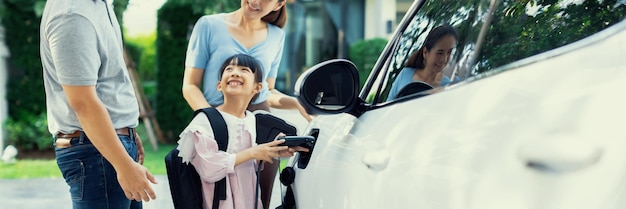 Progressief jong en gelukkig gezin dat in een huis woont met een elektrische auto