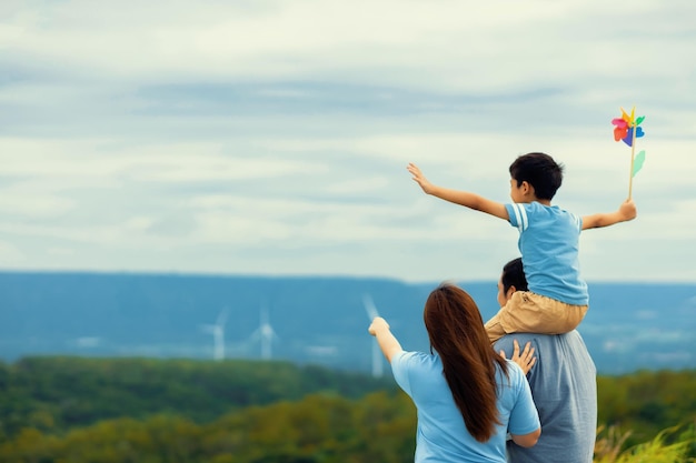 Progressieve gelukkige familie geniet van hun tijd op windpark voor groen energieconcept