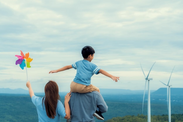 Progressieve gelukkige familie geniet van hun tijd op windpark voor groen energieconcept