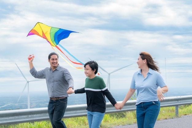 Progressieve gelukkige zorgeloze familie vakantie concept vliegende vlieger met windturbine