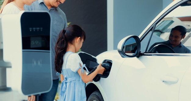 Progressieve jonge ouders en dochter wonen in een huis met een elektrische auto