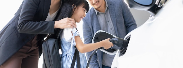 Progressieve jonge ouders en dochter wonen in een huis met een elektrische auto