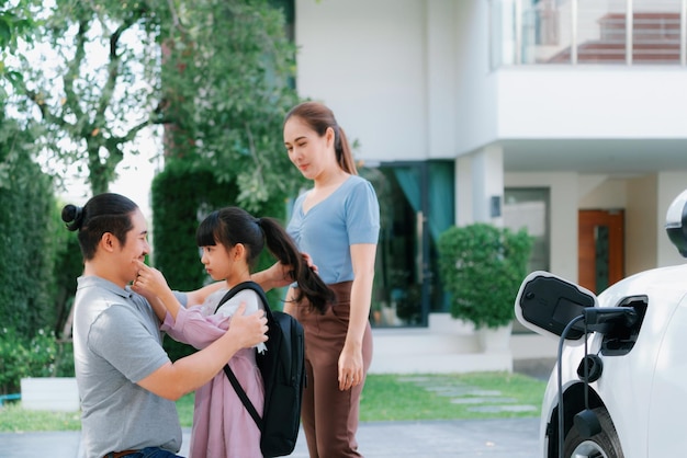 Progressieve jonge ouders en dochter wonen in een huis met een elektrische auto