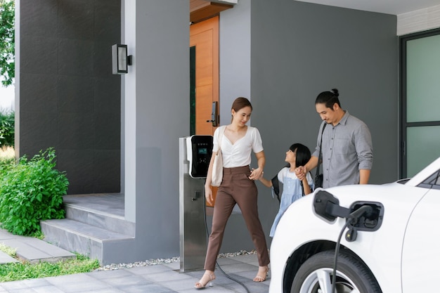 Progressieve jonge ouders en dochter wonen in een huis met een elektrische auto