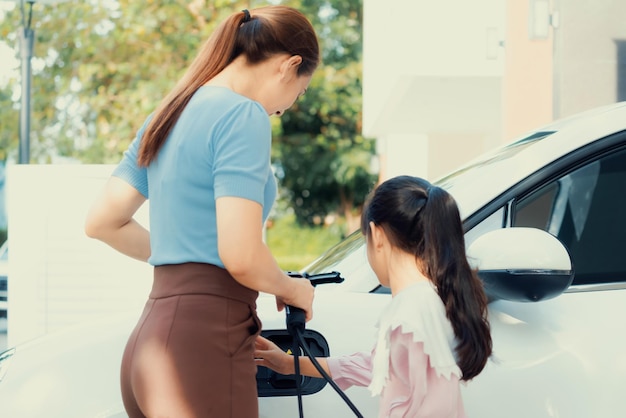 Progressieve levensstijl van moeder en dochter met EV-auto en laadstation