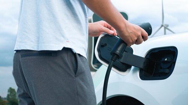 Progressieve man laadt zijn EV-auto op door schone energie op te wekken door windturbine