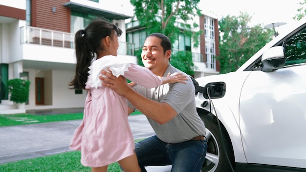 Progressieve vader en dochter installeren stekker van thuislaadstation voor elektrisch voertuig Toekomstige milieuvriendelijke auto met EV-auto's aangedreven door hernieuwbare bron van schone energie