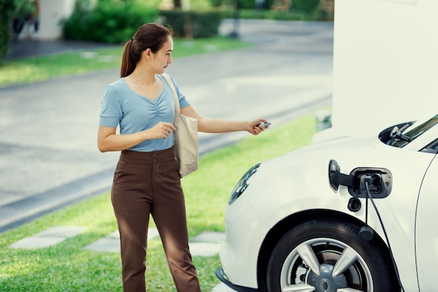 Progressieve vrouw laadt haar EV-auto op bij het laadstation thuis