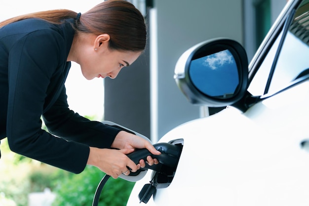 Progressieve vrouw laadt haar EV-auto op bij het laadstation thuis