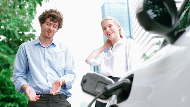 Foto progressieve zakenman en zakenvrouw installeren een oplaadplug van een laadstation op een elektrische auto voordat ze door het stadscentrum rijden eco-vriendelijke oplaadbare auto aangedreven door schone energie