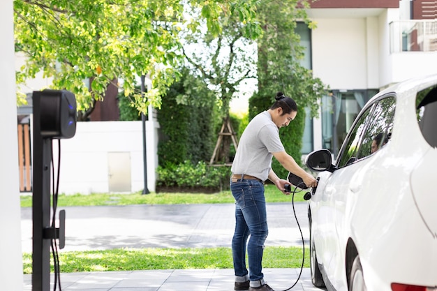 Progressive asian man recharge his EV car at home charging station