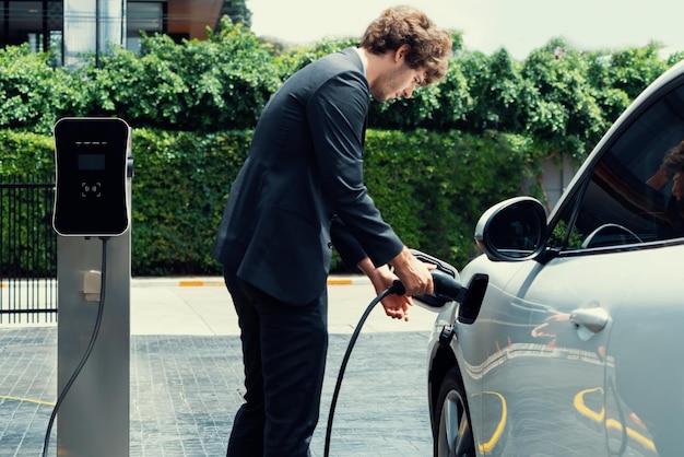 Progressive businessman charging EV car at public parking car charging station