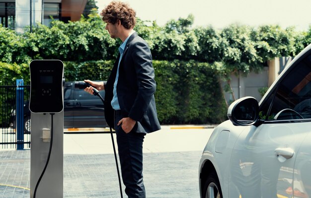 Progressive businessman charging ev car at public parking car charging station