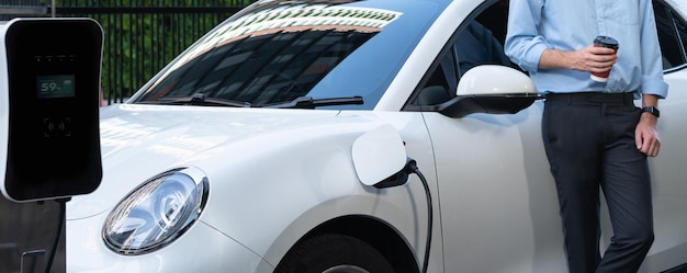 Photo progressive businessman with coffee and ev car at charging station