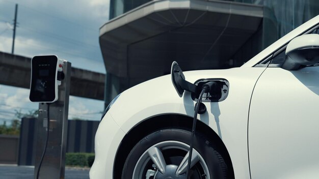 Progressive businesswoman install charger plug from charging station to his electric car before driving around city center Eco friendly rechargeable car powered by sustainable and clean energy