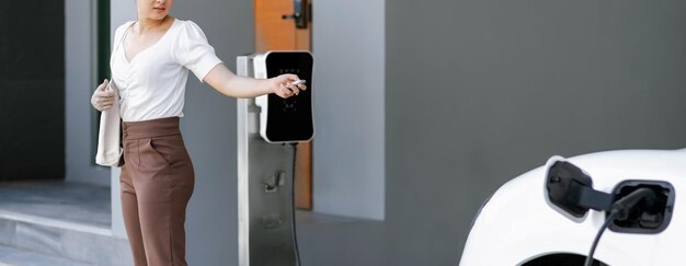 Progressive concept of asian woman and electric car with home charging station