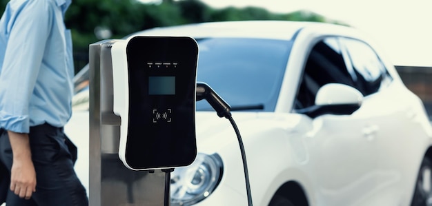 Progressive concept of focus EV car at charging station with blur man background