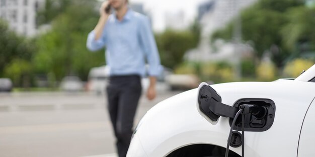 Progressive concept of focus EV car at charging station with blur man background