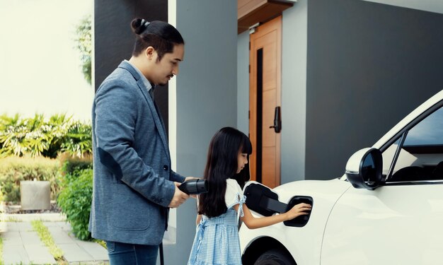 Progressive dad and daughter charging EV car from home charging station