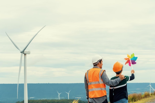 Progressive engineer with his son holding windmill toy in the mountain